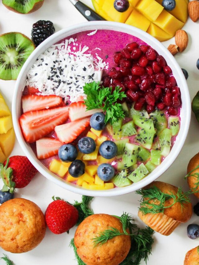 Vibrant smoothie bowl topped with assorted fresh fruits and muffins, perfect for a healthy snack.