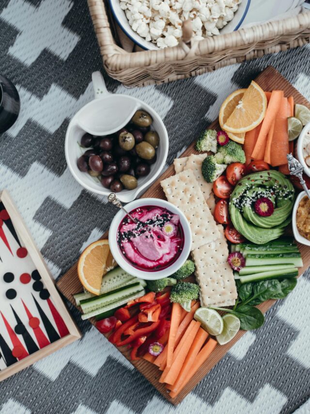 Colorful vegetable platter with dips and crackers, perfect for healthy snacking outdoors.