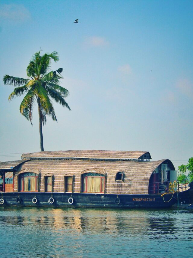 Picturesque view of river with green palms on bank and shabby wooden boathouse under blue sky in tropical countryside