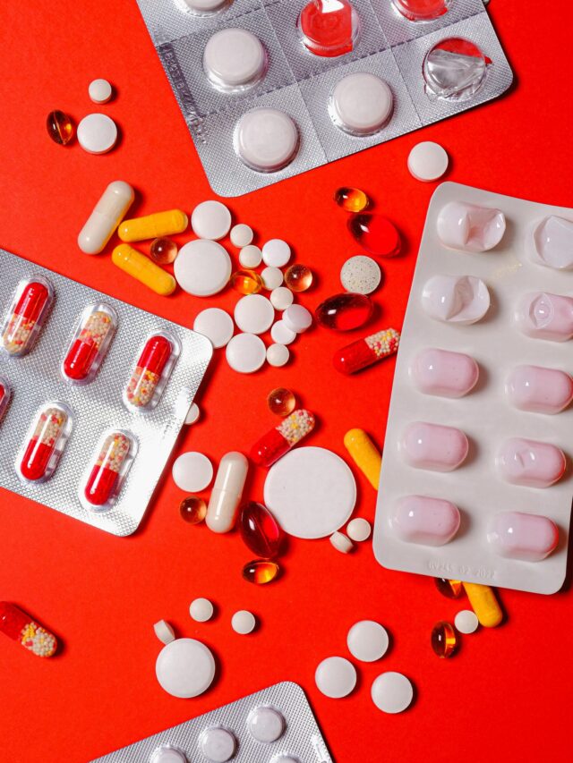 A close-up of various pills and capsules on a vibrant red background, highlighting healthcare and medicine.